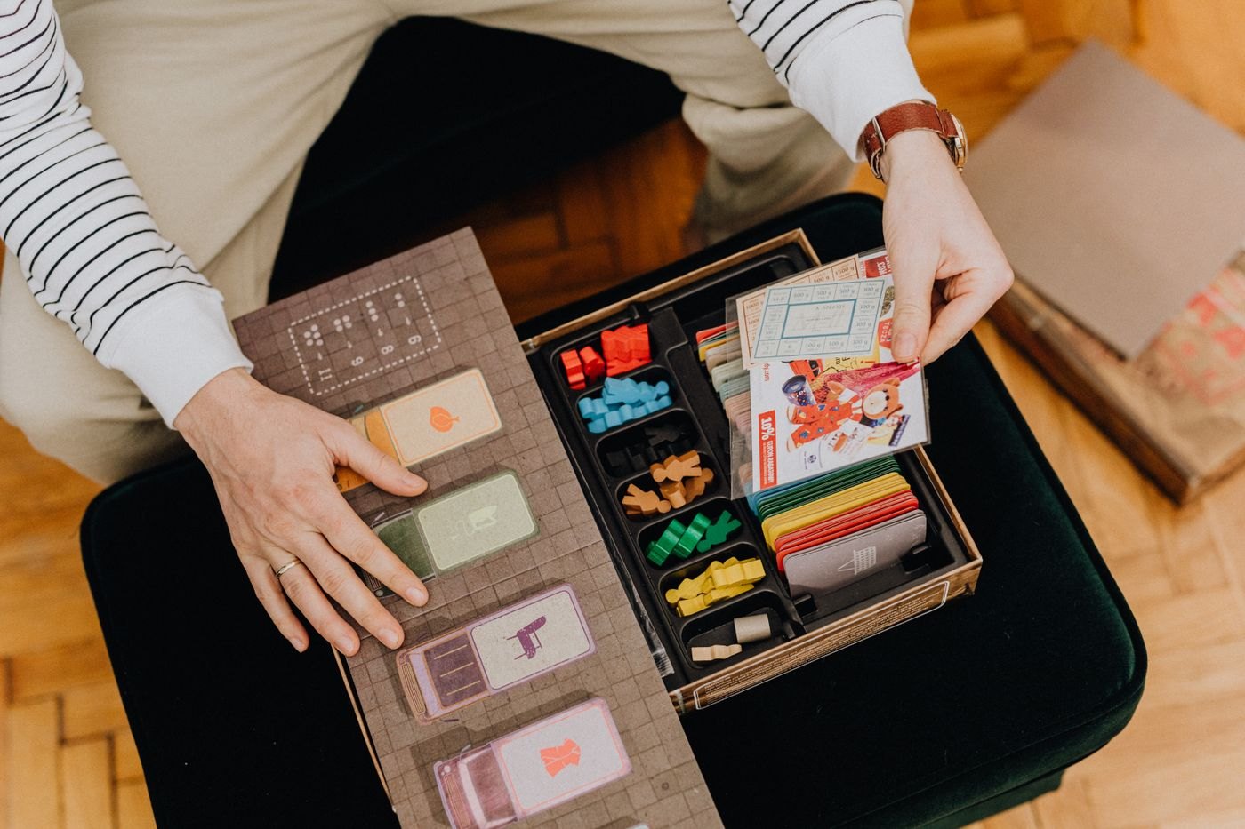 An open board game box with cards and sorted components