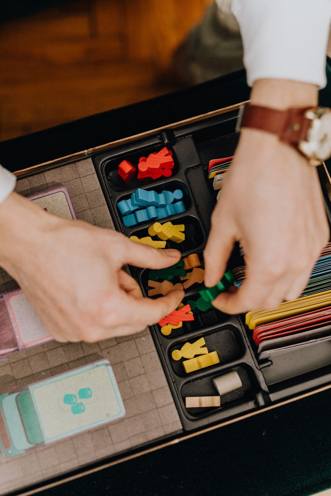 Hands choosing wooden pieces from a game organiser