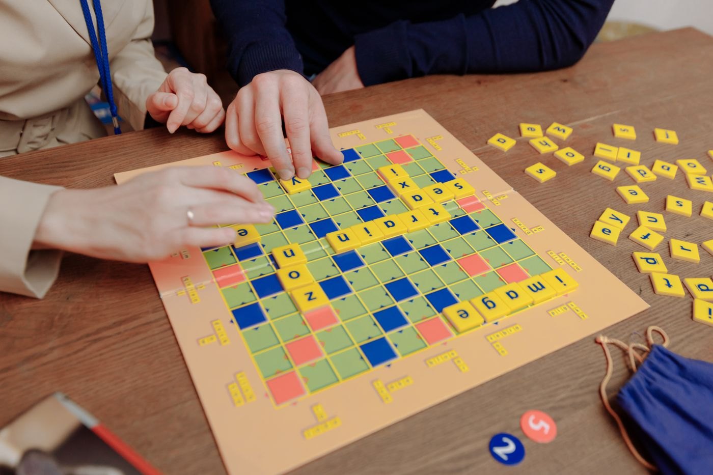 Hands placing letter tiles on a word game board