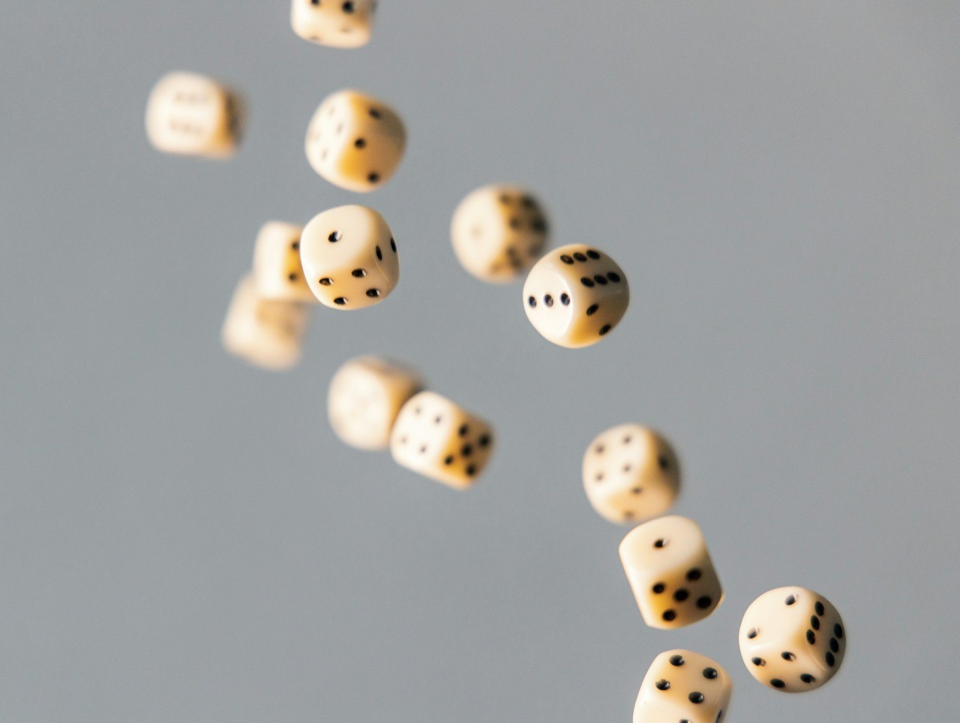Wooden dice falling against a plain grey background