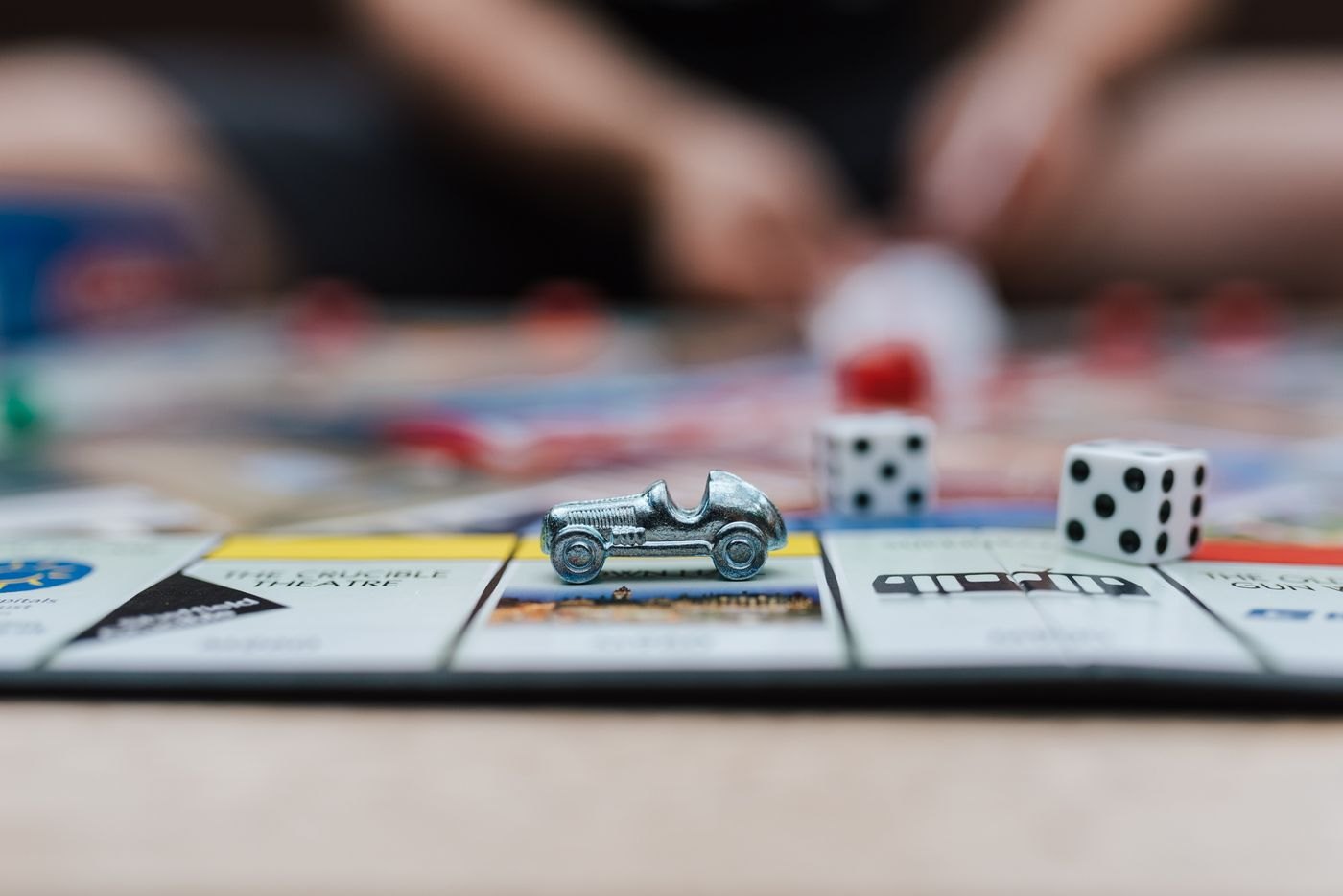 A metal car token and dice on a property board