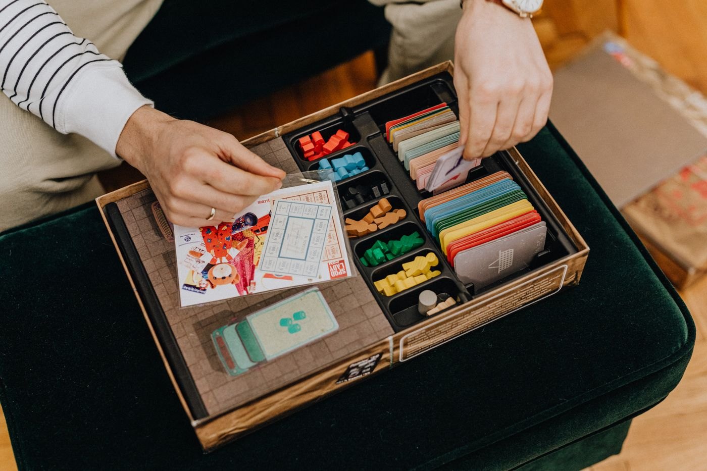 Hands sorting cards back into the compartments of a game box