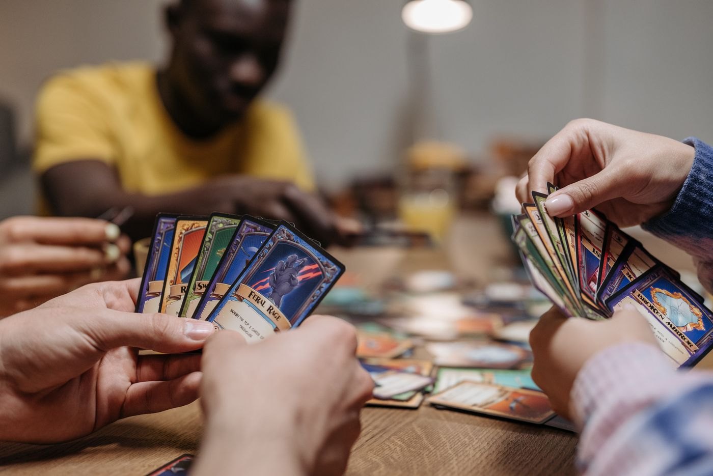 Players holding fans of illustrated cards close to their hands