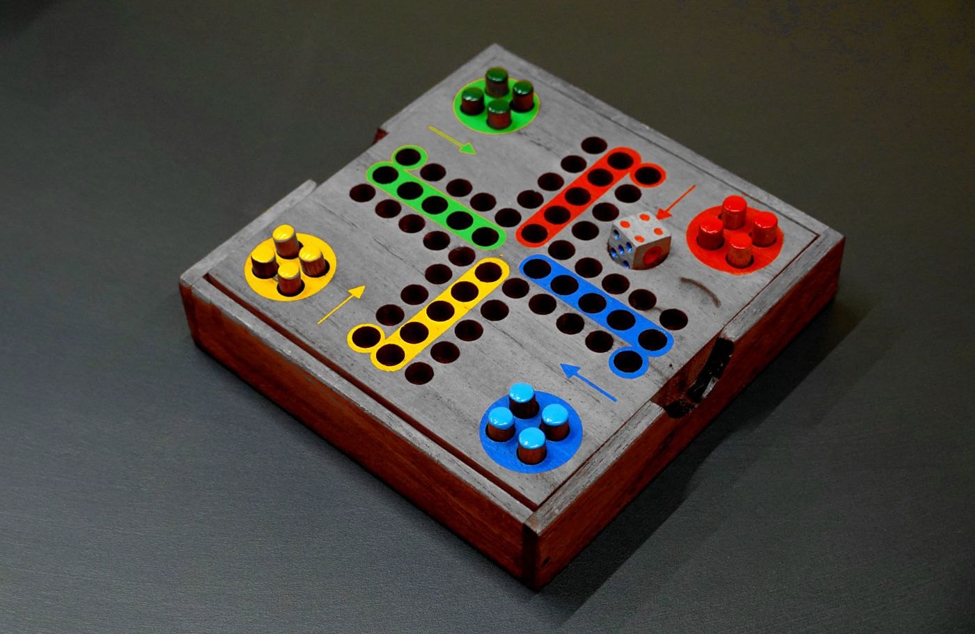 Coloured pawns on a wooden board with a track of spaces
