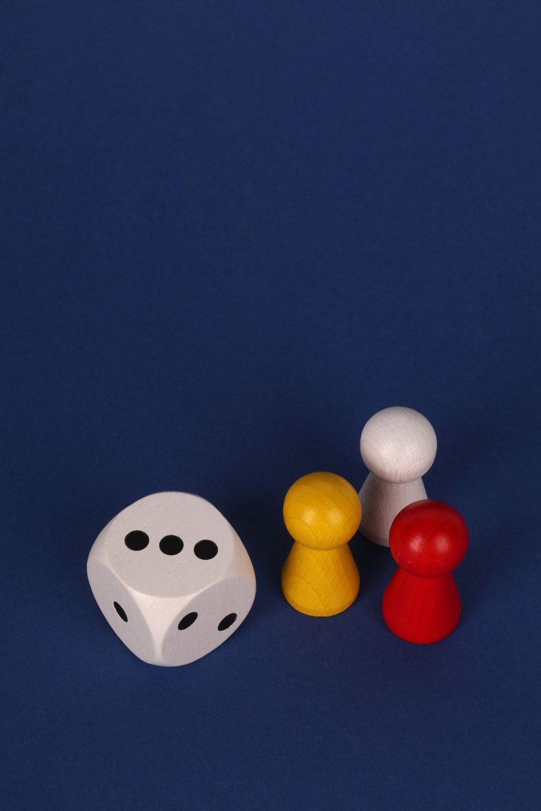 A die beside several differently coloured pawns