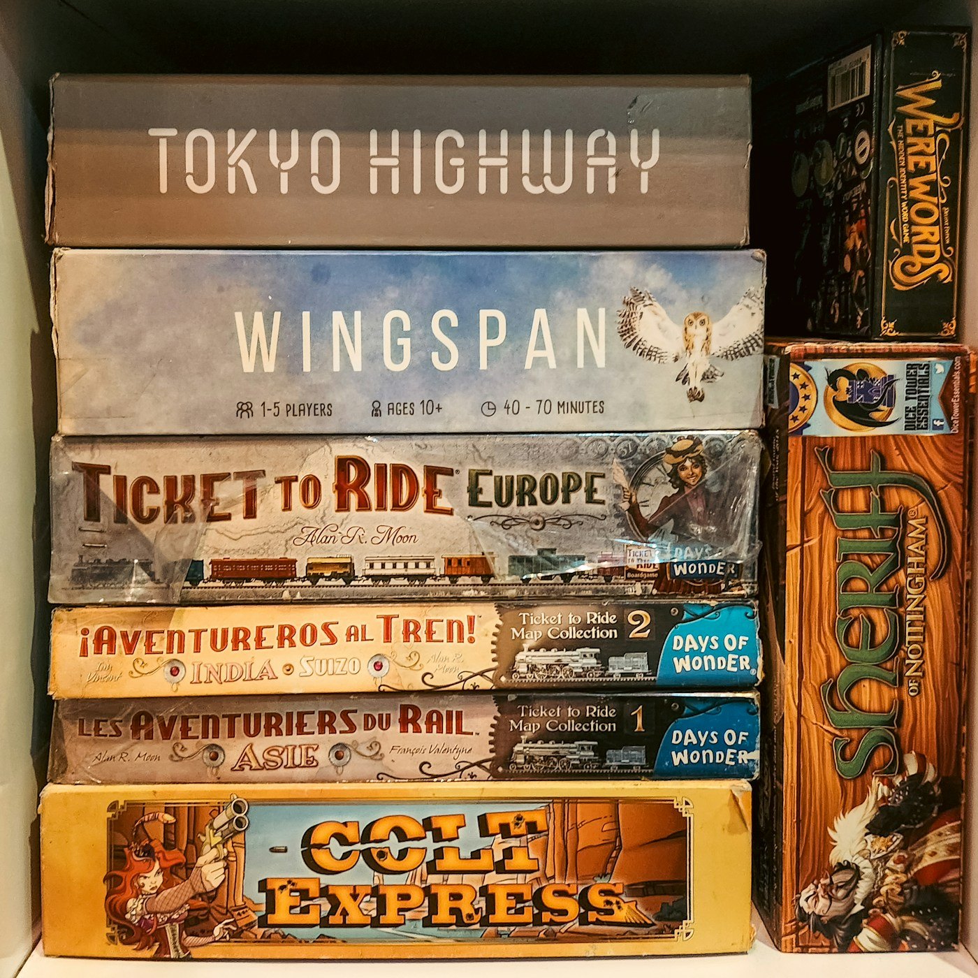 Board game boxes stacked flat in a shelving compartment