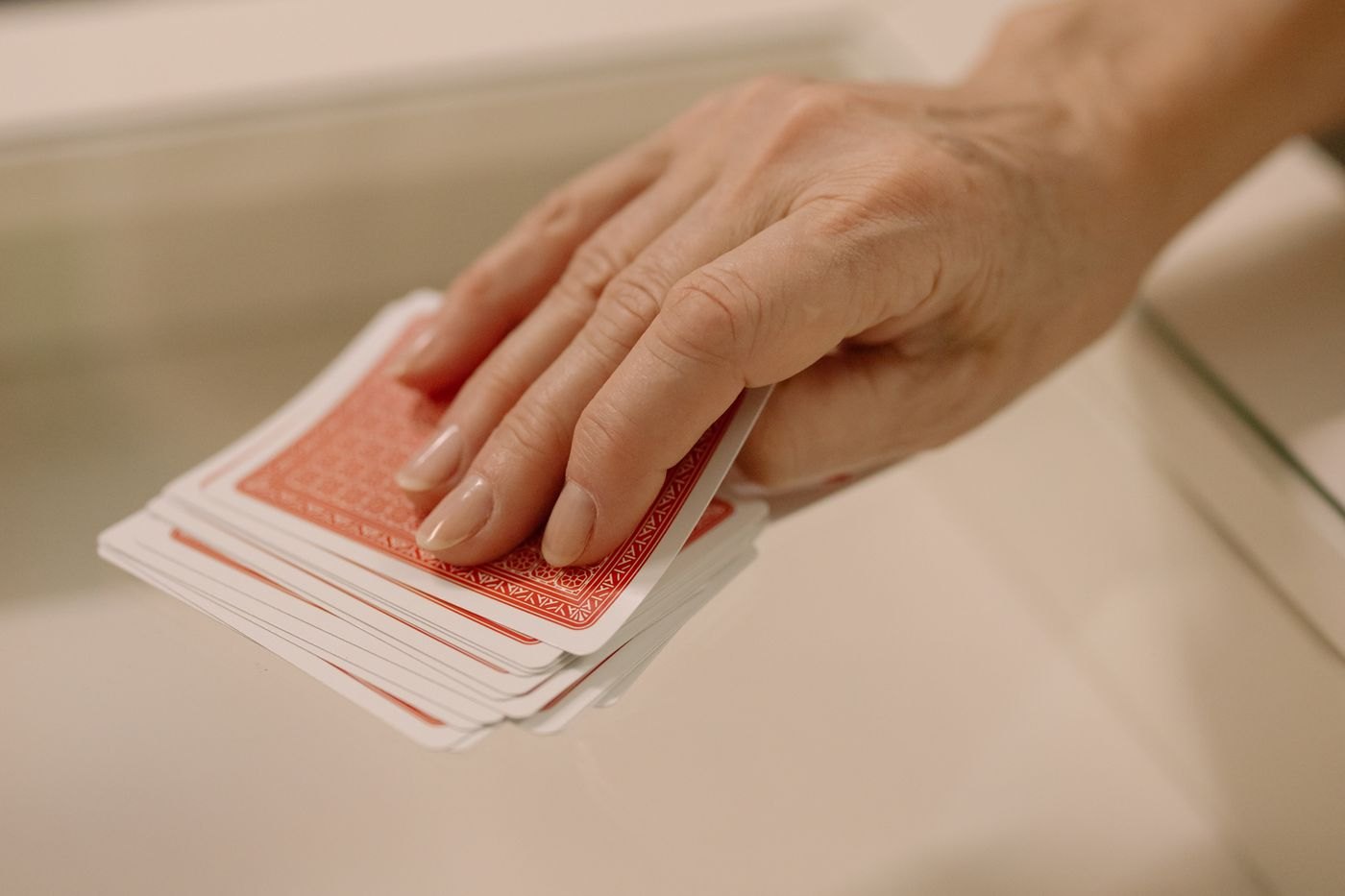 A hand resting lightly on the back of a deck of cards