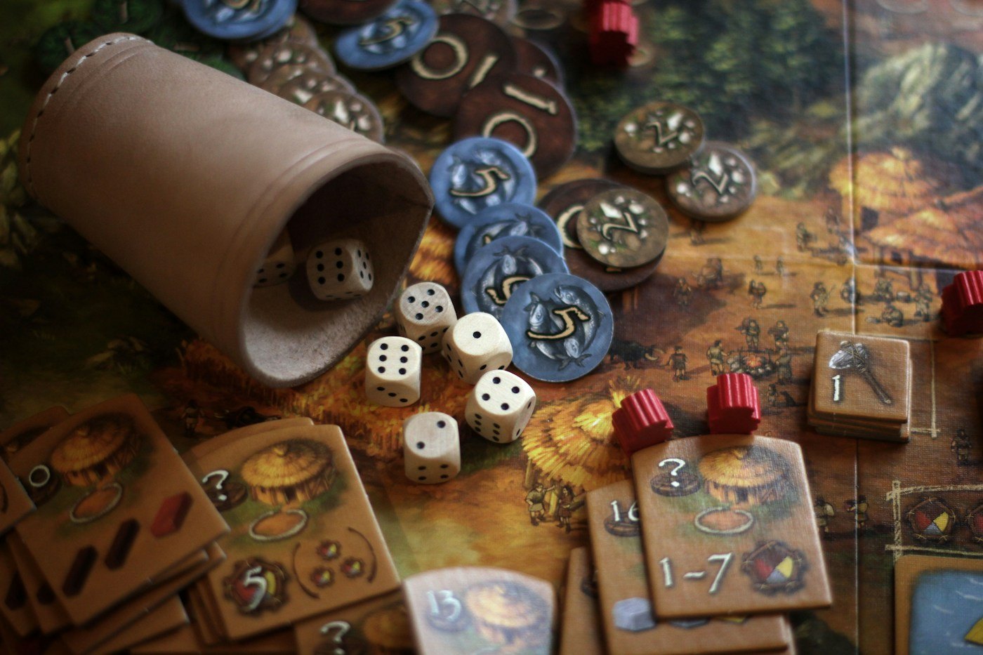 A dice cup, counters and game pieces laid out for play